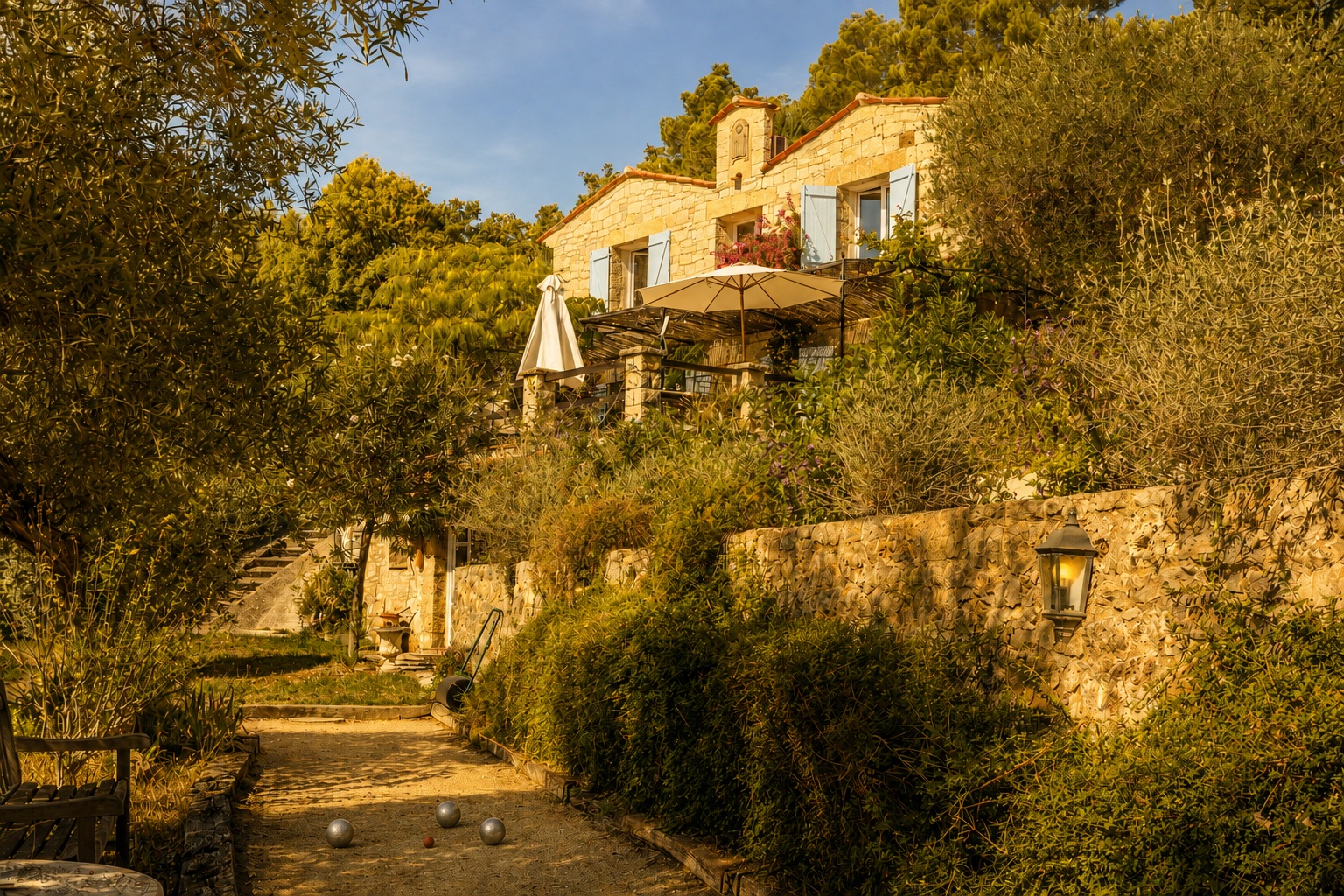 Pétanque court with boules beneath olive trees, overlooking the stone terraces of the Mas