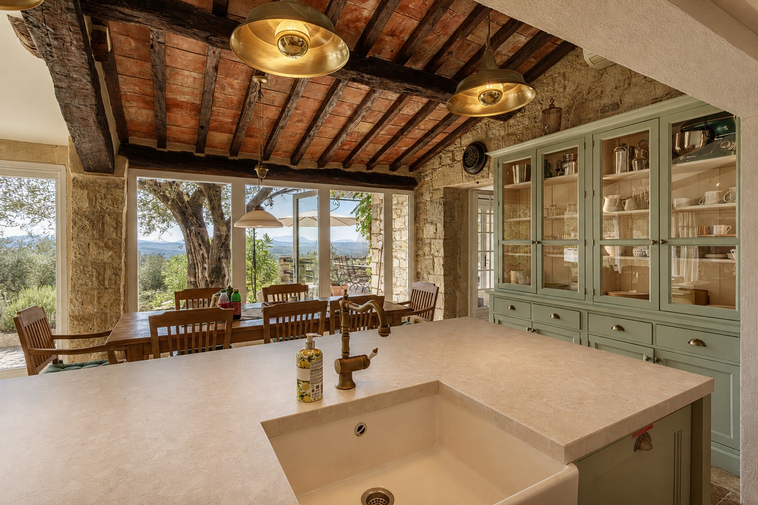 Stone kitchen island facing the breakfast table, olive tree and valley
